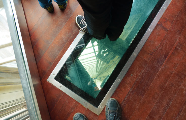 Looking down through the glass bottom and glass walls of the elevator at the CN Tower  