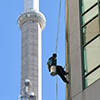 a man is washing the windows of condo building in downtown Toronto, with the CN tower in the background.  