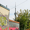 a graffiti covered wall in a parking lot, with the CN tower in the background.  