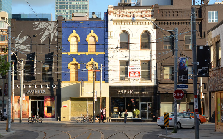 a couple of older storefronts on Queen Street West, Civello, Aveda, Babur Indian Cuisine, and two that are boarded up.  They are all three storey buildings.