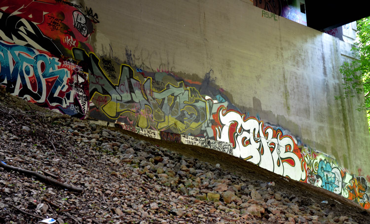 graffiti, mostly tags, painted under a bridge