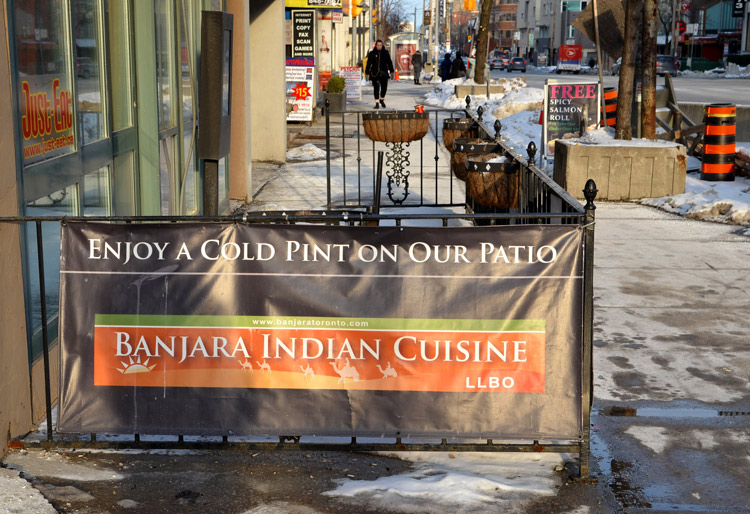 sign around a sidewalk patio of the Banjara Indian restaurant, in the winter