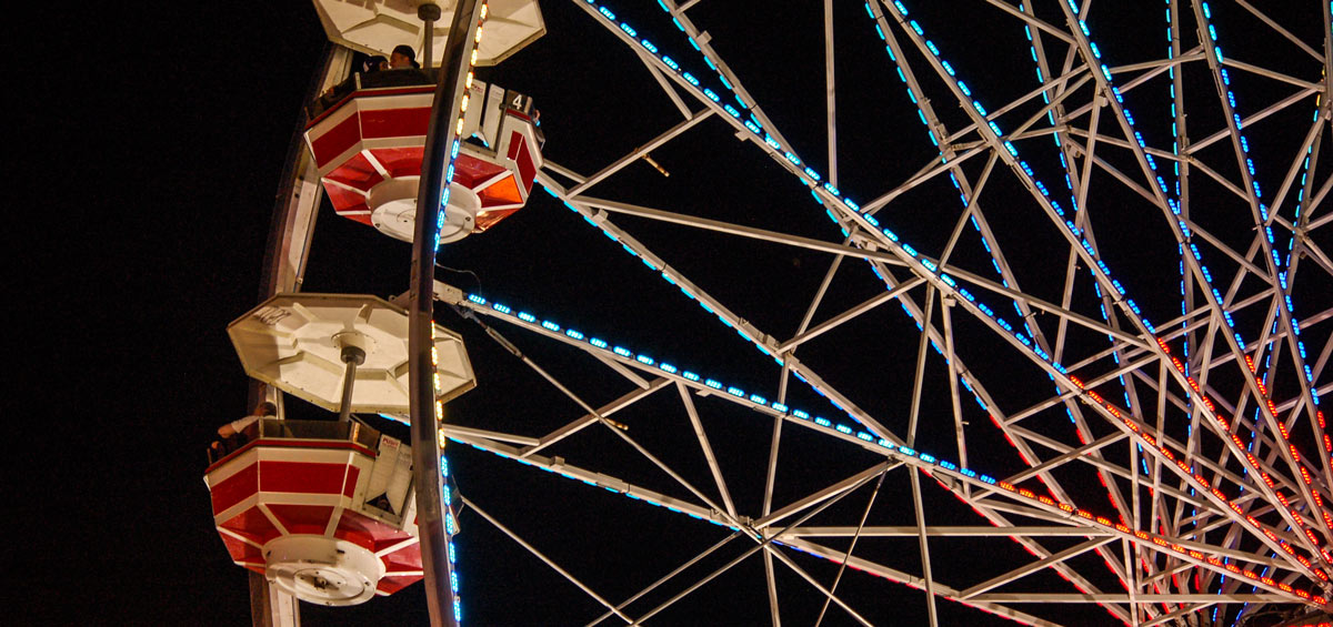 crowds at the CNE midway on a Saturday evening as the sky gets darker and the lights get brighter