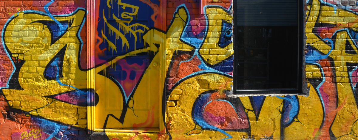 A side of a building is totally covered in very bright coloured graffiti 