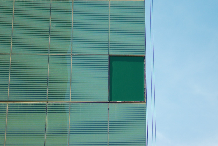 a green square window on a light blue building