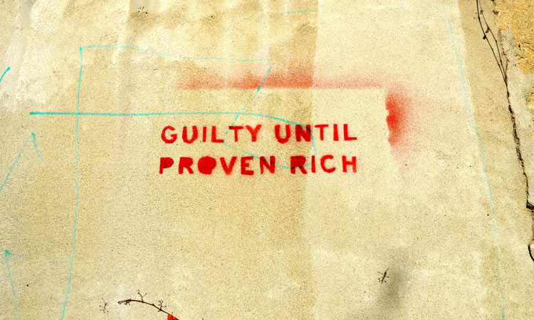 red stencil on a stucco wall, words that say guilty under proven rich