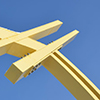 close up shot of the yellow arches of a bridge support against the blue sky.  