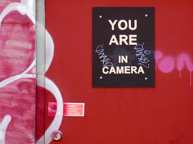 sign on a red door that says you are in camera