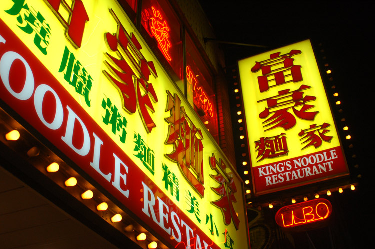brightly lit exterior sign for Kings Noodle restaurant taken at night