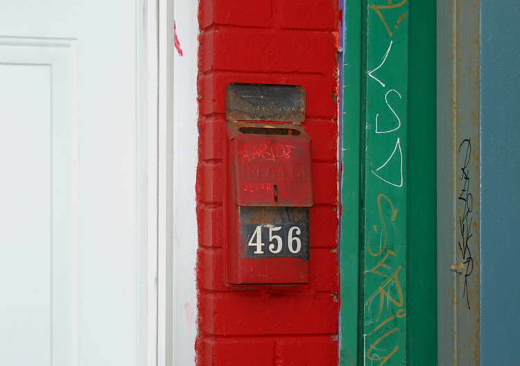 mailbox with the number 456 on it, on a red and green wall and beside a white door
