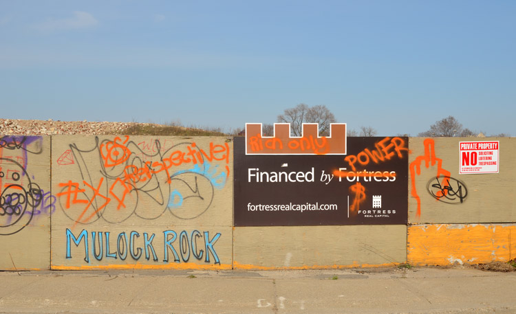 Protest graffiti sprayed on the fence surrounding a construction site.. 