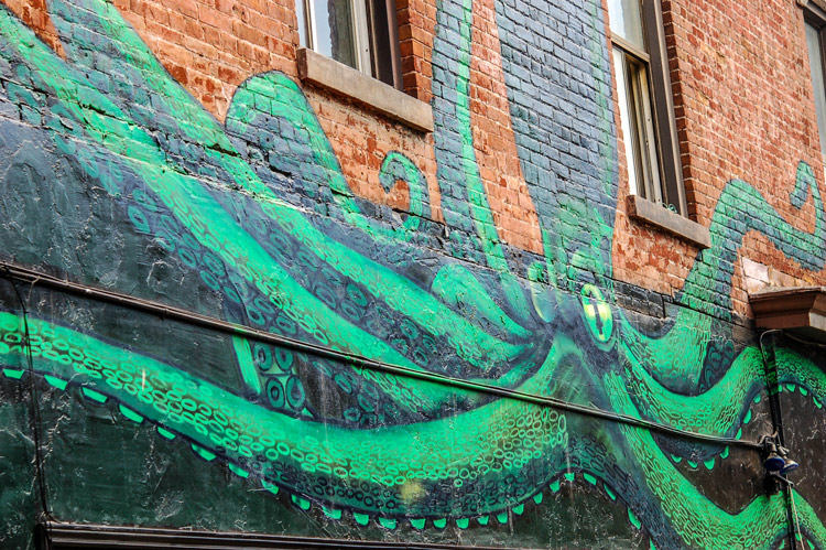 a large green octopus painted onto a brick wall