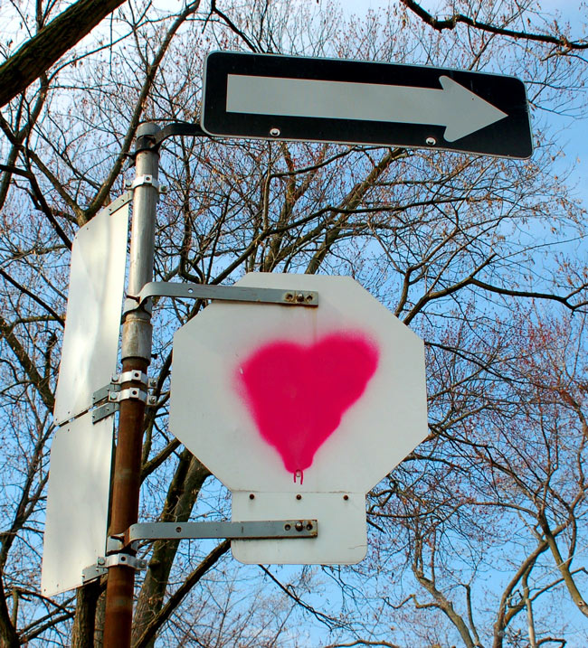 pink heart spray painted on the back of a stop sign